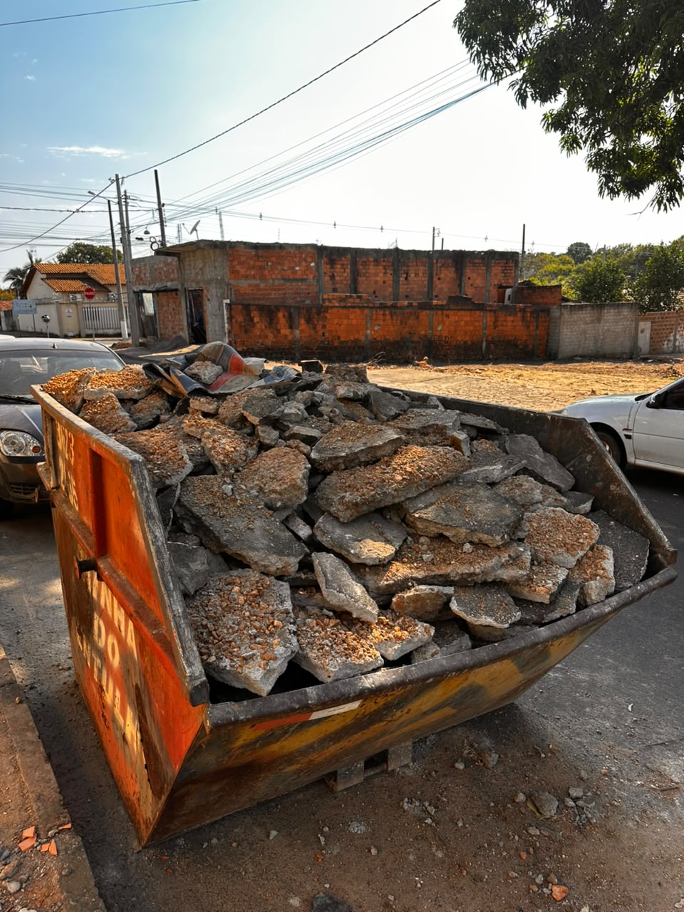 Caçamba carregada com pedaços de concreto e entulho